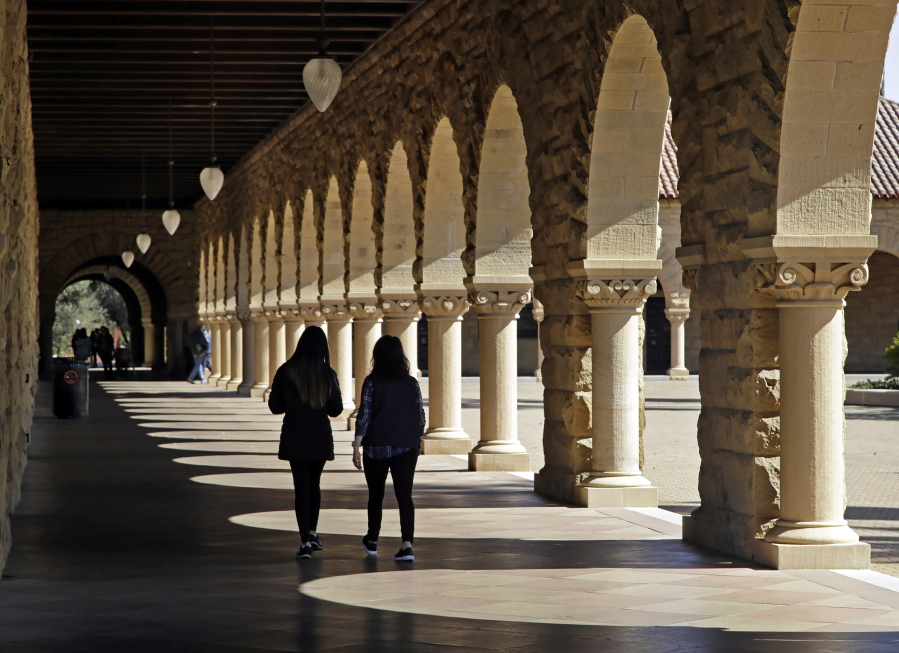 FILE -- Students walk on the Stanford University campus in Stanford, Calif, March 14, 2019. When students at Stanford University return to campus in January 2022, they'll be barred from holding parties or other big gatherings for two weeks.