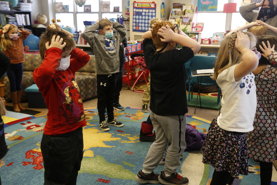 Second-graders hold their heads as they talk about "thoughts" and how they compare with "feelings" and resulting "actions," at Paw Paw Elementary School on Thursday, Dec. 2, 2021, in Paw Paw, Michigan. Their teacher is one of many in the school trained to use a curriculum created at the University of Michigan called TRAILS. Research suggests TRAILS lessons for at-risk kids can reduce depression and improve coping skills -- something district officials say has been particularly important during the pandemic.