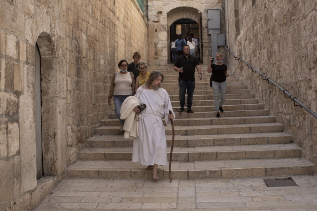 An American pilgrim walks to the Church of the Holy Sepulchre, where many Christians believe Jesus was crucified, buried and rose from the dead, in the Old City of Jerusalem, Tuesday, Nov. 30, 2021. As countries shut their doors to foreign tourists or reimpose restrictions because of the new omicron variant of the coronavirus, tourism that was just finding it's footing again could face another major pandemic slowdown amid the uncertainty about the new strain.