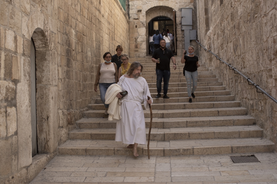 An American pilgrim walks to the Church of the Holy Sepulchre, where many Christians believe Jesus was crucified, buried and rose from the dead, in the Old City of Jerusalem, Tuesday, Nov. 30, 2021. As countries shut their doors to foreign tourists or reimpose restrictions because of the new omicron variant of the coronavirus, tourism that was just finding it's footing again could face another major pandemic slowdown amid the uncertainty about the new strain.