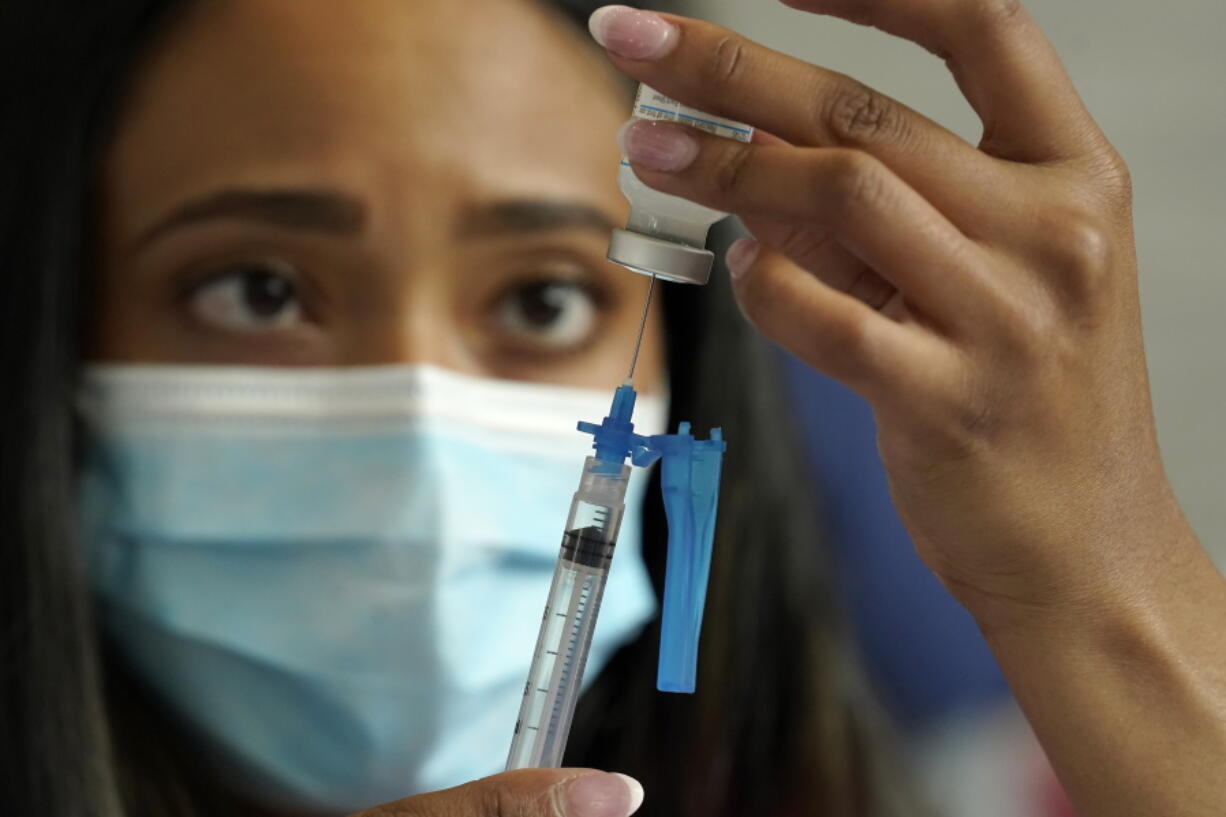 FILE - Licensed practical nurse Yokasta Castro, of Warwick, R.I., draws a Moderna COVID-19 vaccine into a syringe at a mass vaccination clinic, May 19, 2021, at Gillette Stadium, in Foxborough, Mass. While all eyes are on the new and little-understood omicron variant, the delta form of the coronavirus isn't finished wreaking havoc in the U.S. There is much that is unknown about omicron, including whether it is more contagious than previous versions, makes people sicker or more easily thwarts the vaccine or breaks through the immunity that people get from a bout of COVID-19.