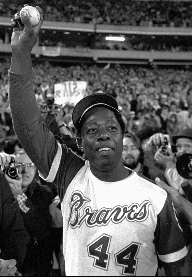 Baseball player Hank Aaron holds aloft the ball he hit for his 715th career home in Atlanta. Aaron, who endured racist threats with stoic dignity during his pursuit of Babe Ruth but went on to break the career home run record in the pre-steroids era, died early Jan. 22, 2021. He was 86.