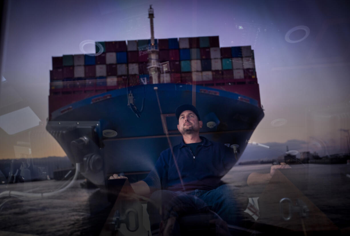 Capt. Mike Johnson reflected in the wheelhouse of the tugboat Delta Teresa where he has a front-row seat to the size and the scale of the container ship that he's helping to bring into the port of Long Beach Friday, Dec. 3, 2021, in Port of Long Beach, Calfornia. (Allen J.