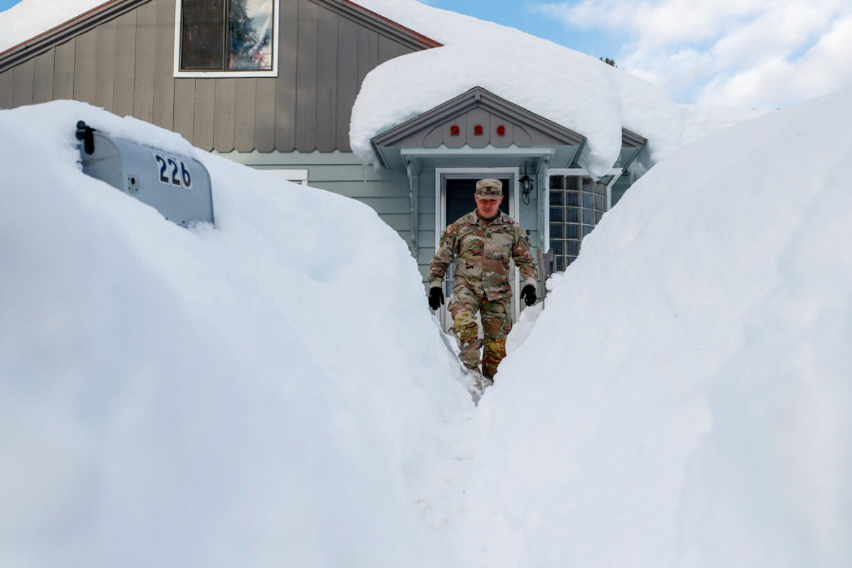Capt. Luis Torres wades through the snow after knocking on the door of a house Monday, Jan. 10, 2022, in Leavenworth, Washington. The National Guard was dispatched to the city to assist in the dig-out.
