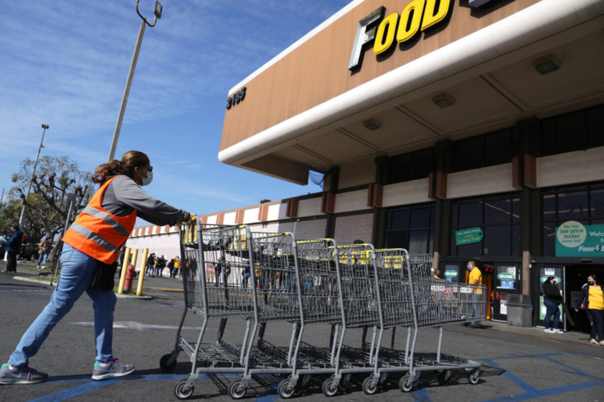 A grocery worker collects carts outside of the Food 4 Less on South Street in North Long Beach, California on Wednesday, February 3, 2021.