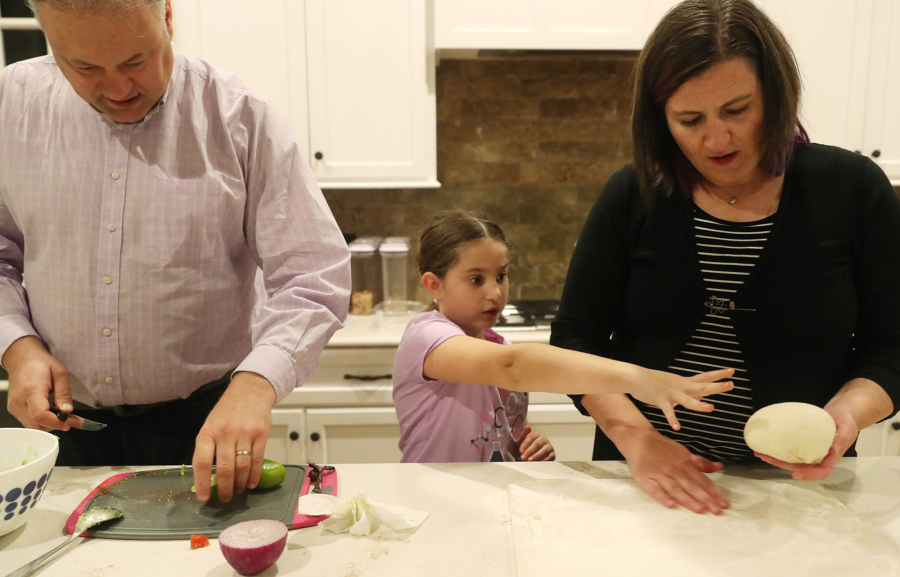 Ian and Liza Papautsky, with their daughter Sasha, 8, prepare dinner at their home  in the western suburbs on Jan. 6, 2022. (John J.