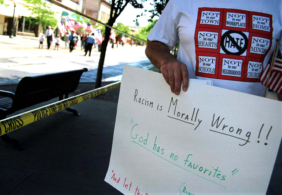 An anti-racism demonstrator holds a sign as members of white supremacist group Aryan Nations march July 7, 2001 in the streets of Coeur d'Alene, Idaho. (Jerome A.