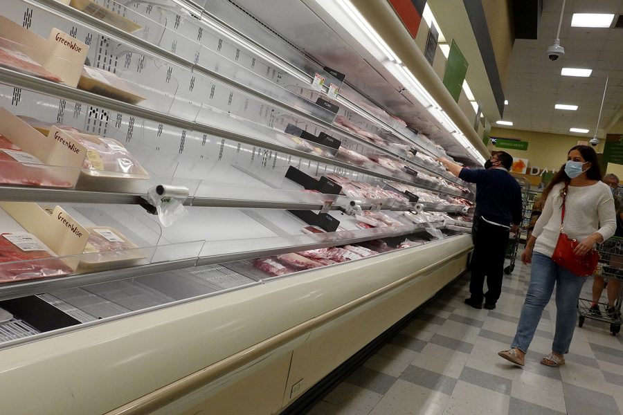 Shelves displaying meat are partially empty as shoppers makes their way through a supermarket on Jan. 11, 2022, in Miami, Florida.