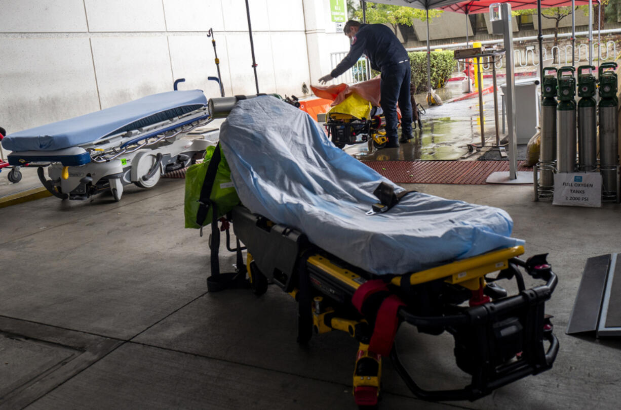 On a cold rainy day a paramedic places a blanket on a patient he has brought to the Emergency Department at Martin Luther King Jr. Community Hospital located on Wednesday, Dec. 29, 2021, in in the Willowbrook neighborhood of Los Angeles, California.