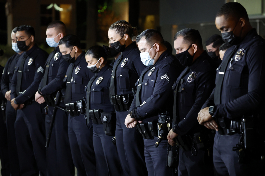 Los Angeles Police Department officers bow their heads in prayer to honor Officer Fernando Arroyos, who was shot and killed during an armed robbery attempt Monday, outside the Olympic Community Police Station, on Jan. 12, 2022, in Los Angeles.