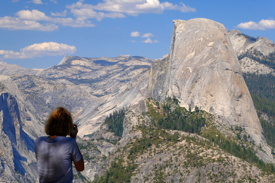 A visitor snaps photos of Half Dome from Washburn Point in Yosemite National Park on Aug. 4, 2021. The peak of Half Dome is over 8,000 feet above sea level.