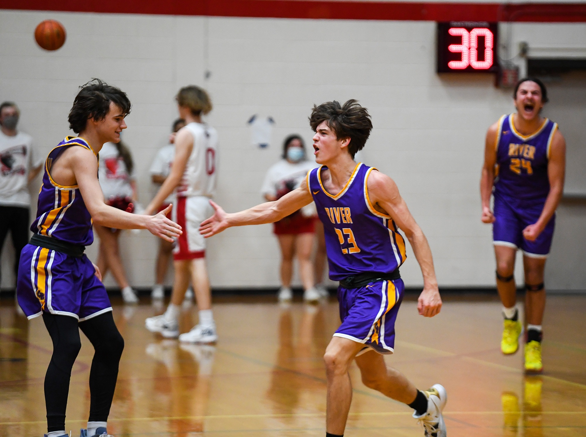 Columbia River freshman Aaron Hoey, center, celebrates a buzzer beater to end the first half with Columbia River freshman John Reeder, left, on Wednesday, Jan. 19, 2022, during the Rapids’ 48-38 win against the Trappers at Fort Vancouver High School.