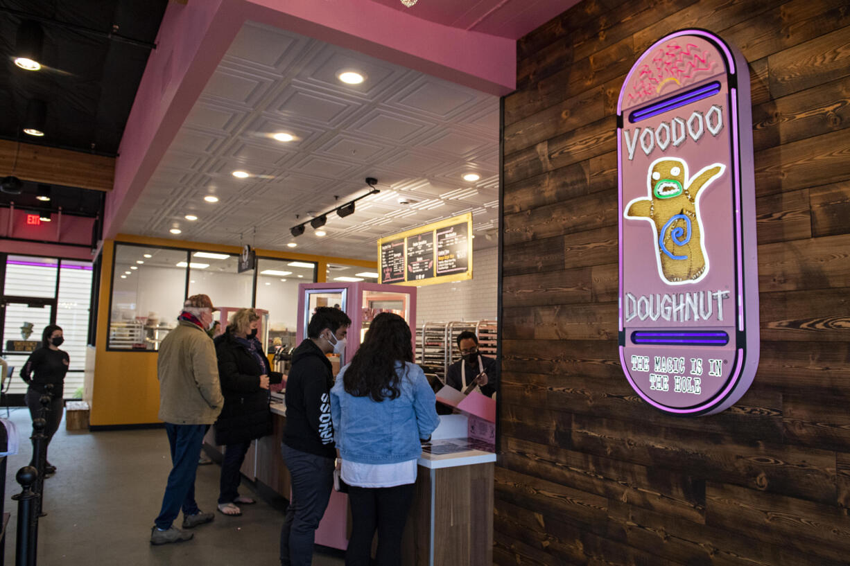 Employees help customers at check-out during the grand opening of the new Voodoo Doughnut at Vancouver Mall on Tuesday morning, Jan.11, 2022.