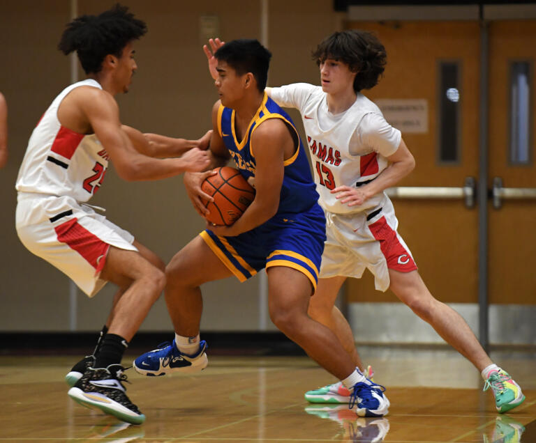 Kelso junior Naiser Lukas, center, protects the ball while Camas senior Quentin Allen, left, goes for a steal Friday, Jan. 21, 2022, during the Hilanders’ 83-38 loss to the Papermakers at Camas High School.