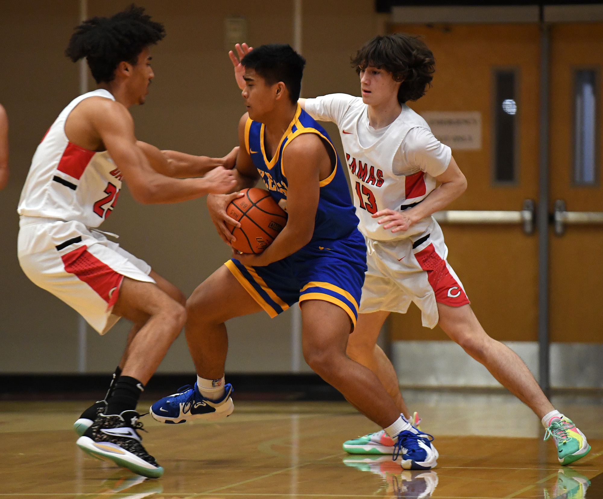 Kelso junior Naiser Lukas, center, protects the ball while Camas senior Quentin Allen, left, goes for a steal Friday, Jan. 21, 2022, during the Hilanders’ 83-38 loss to the Papermakers at Camas High School.