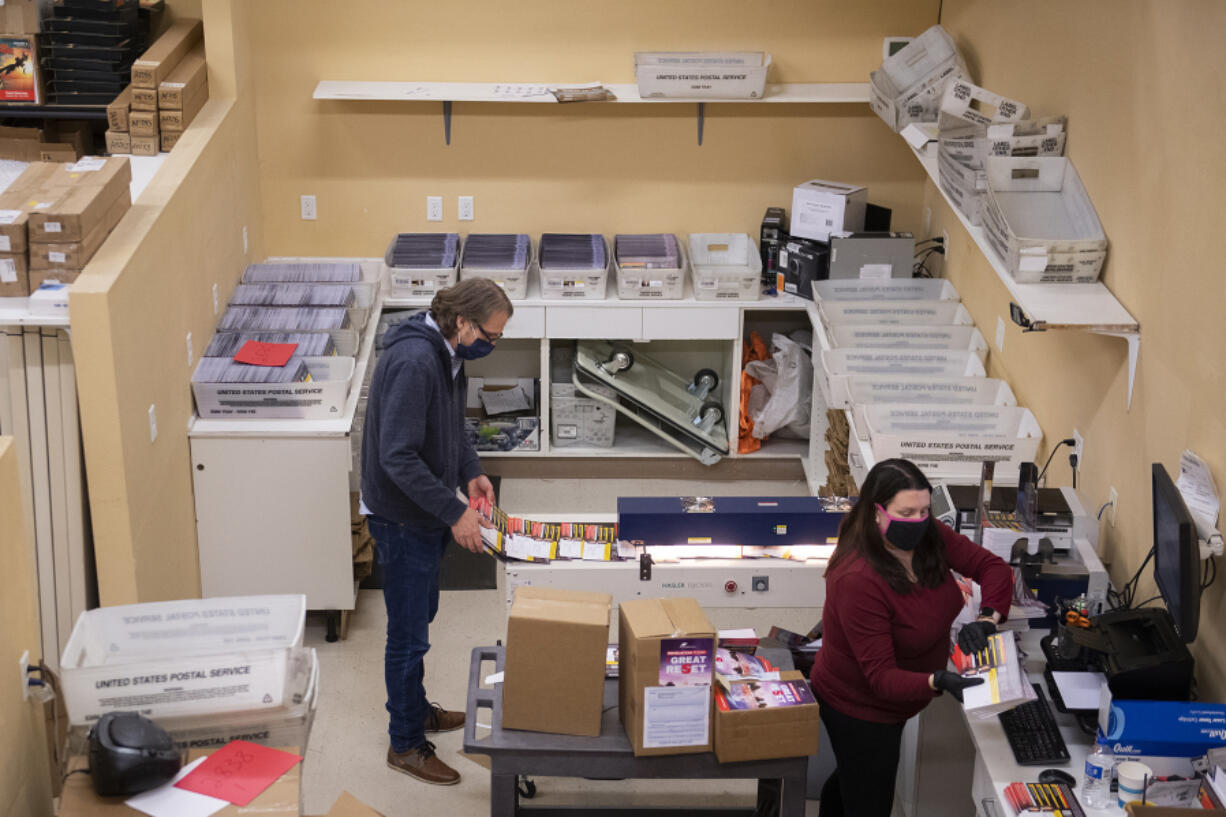 Larry Witzel, founder and president of SermonView, joins mailhouse technician Hannah Gill as they prepare invitations to be mailed from their Vancouver office. SermonView was among those impacted by the early end of a federal aid program to pandemic-hit businesses.