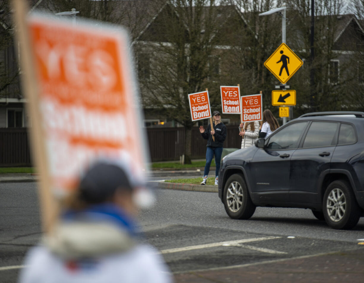 Supporters of the Ridgefield schools bond wave signs Friday at the intersection of Pioneer Street and Royle Road in Ridgefield. Ballots for the upcoming Feb. 8 special election were sent to voters Friday.