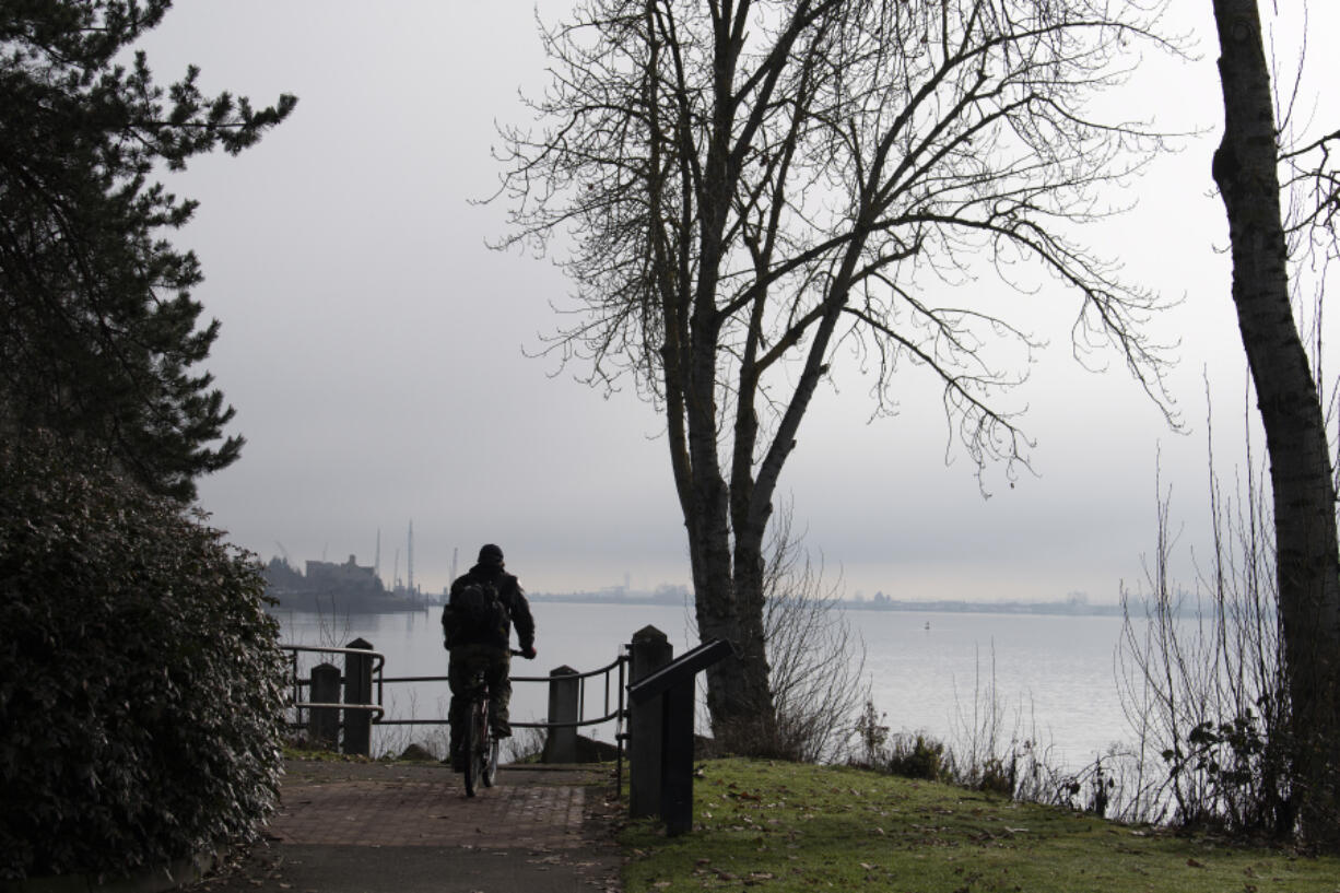 A cyclist takes in a foggy view Monday morning as winter air persists along the Columbia River at the Vancouver waterfront on Monday morning. The foggy mornings followed by sunny afternoons should remain through the week, before the rain returns next week, according to forecasters.