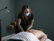 Bre'Anna Glynn, owner of The Eucalyptus Lounge, works with client Bob Engle in her downtown Vancouver massage room. The business has an established clientele, including many people of color, but is struggling as people distance themselves due to the omicron variant.