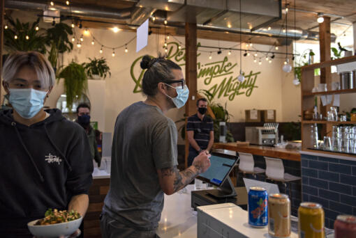 Stephen Chan of Mighty Bowl, left, serves up a lunch order as owner Steve Valenta chats with a customer in downtown Vancouver. In the fourth quarter of last year, Valenta's costs for food increased 24 percent. They had been steadily rising throughout the pandemic. His costs for to-go packaging rose 60 percent.