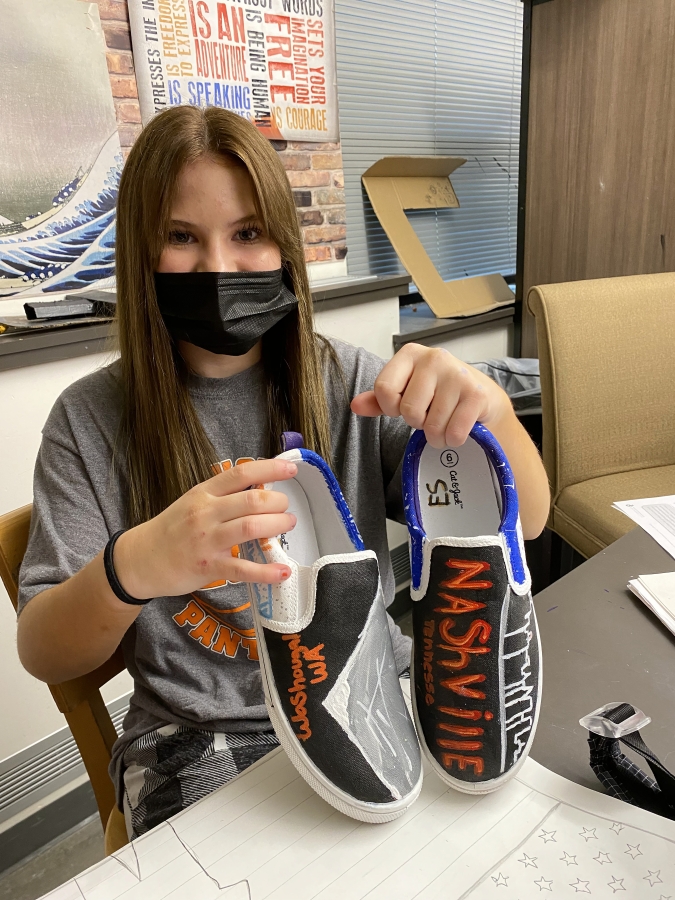 Jemtegaard Middle School student Ellie Sneer holds shoes she designed for an art project. The shoes show Sneer's roots in Washougal, love of volleyball, and the skyline of Nashville, Tenn., where Sneer hopes to move someday to attend Belmont University.