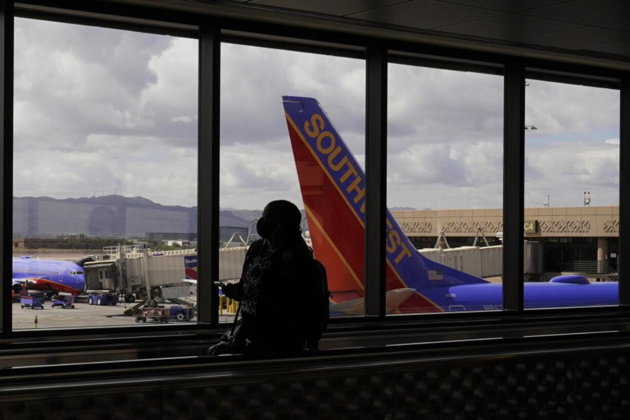 FILE - A passenger walks past a Southwest Airlines plane at Sky Harbor International Airport in Phoenix, March 26, 2021. AT&T and Verizon have agreed to delay the launch of a new slice of 5G service by two weeks after airlines and the nation's aviation regulator complained about potential interference with systems on board planes.