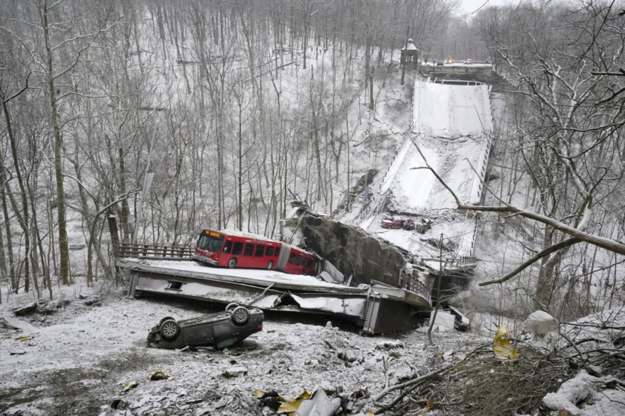 A Port Authority bus that was on a bridge when it collapsed Friday Jan. 28, 2022, is visible in Pittsburgh's East End.  A two-lane bridge collapsed in Pittsburgh early Friday, prompting rescuers to rappel nearly 150 feet (46 meters) while others formed a human chain to help rescue multiple people from a dangling bus.(AP Photo/Gene J.