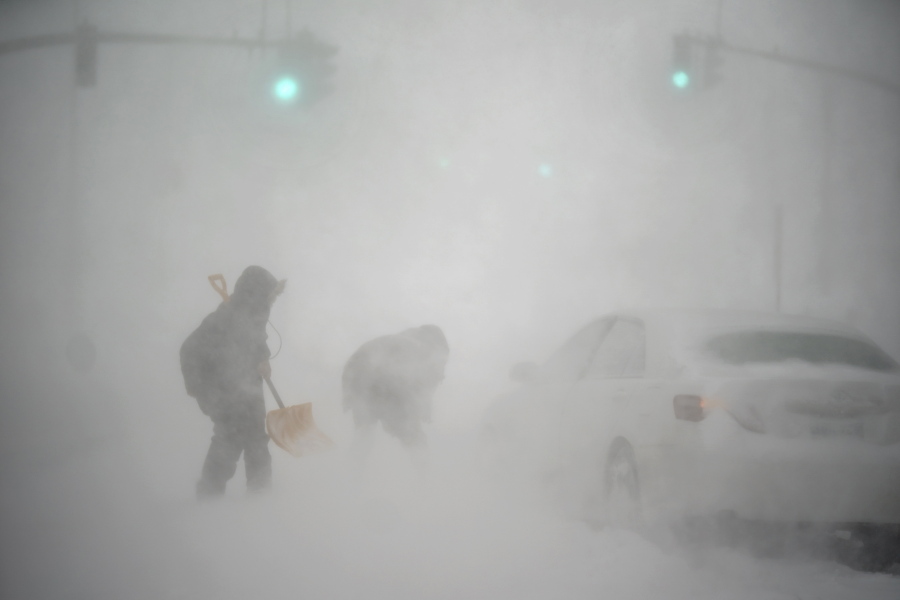 A stranded motorist, at right, gets help shoveling out their car from a passerby with a shovel in Providence, R.I., Saturday, Jan. 29, 2022. A powerful nor'easter swept up the East Coast on Saturday, threatening to bury parts of 10 states under deep, furiously falling snow accompanied by coastal flooding and high winds that could cut power and leave people shivering in the cold weather expected to follow.