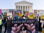 FILE - Stephen Parlato of Boulder, Colo., holds a sign that reads "Hands Off Roe!!!" as abortion rights advocates and anti-abortion protesters demonstrate in front of the U.S. Supreme Court, on Dec. 1, 2021, in Washington. With Roe v.