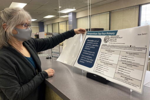 Deborah Moody, an administrative clerk at the Alaska Division of Elections office in Anchorage, Alaska, looks at an oversized booklet explaining election changes in the state on Jan. 21, 2022. Alaska elections will be held for the first time this year under a voter-backed system that scraps party primaries and sends the top four vote-getters regardless of party to the general election, where ranked choice voting will be used to determine a winner. No other state conducts its elections with that same combination.