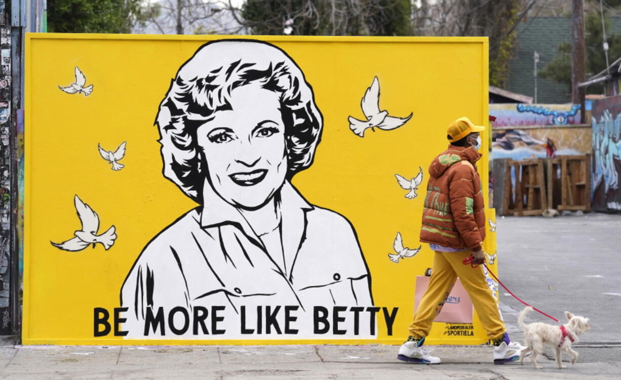 A man walks a dog past a new mural of the late actress Betty White by artist Corie Mattie in Los Angeles.