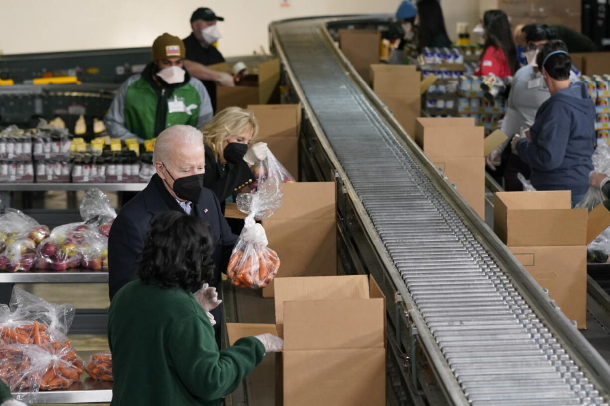 President Joe Biden and first lady Jill Biden pack produce while they volunteer at hunger relief organization Philabundance, Sunday, Jan. 16, 2022, in Philadelphia.