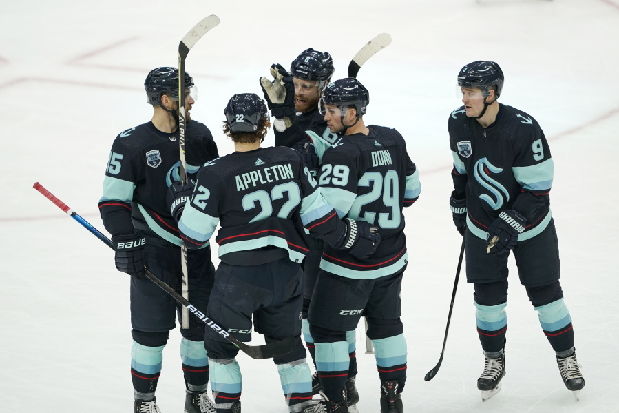 Seattle Kraken defenseman Vince Dunn (29) is greeted by teammates after he scored a goal against the Chicago Blackhawks during the second period of an NHL hockey game, Monday, Jan. 17, 2022, in Seattle. (AP Photo/Ted S.