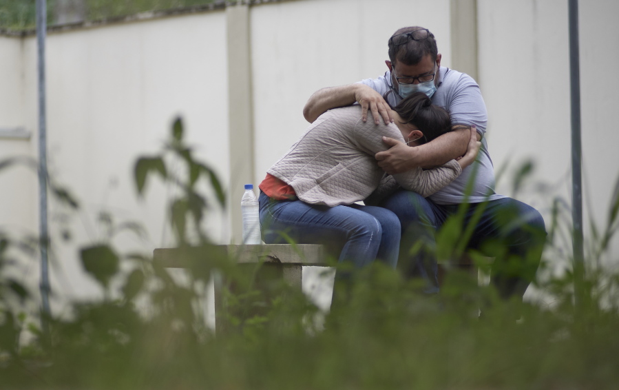 A couple embraces as they wait for information about missing relatives after a massive slab of rock broke away from a cliff and toppled onto pleasure boaters at Furnas reservoir on Saturday, killing at least seven people, near Capitolio city, Brazil, Sunday, Jan. 9, 2022.
