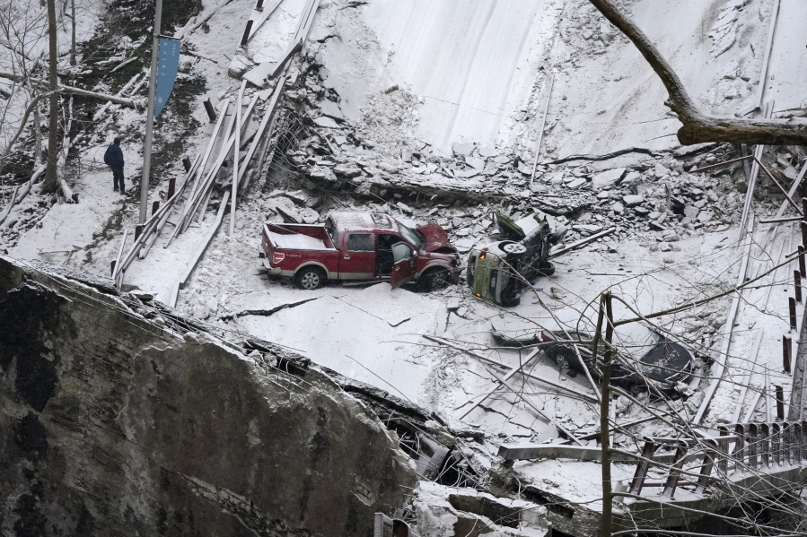 Vehicles that were on a bridge when it collapsed are visible, Friday Jan. 28, 2022, in Pittsburgh's East End. When the bridge collapsed, rescuers rappeled nearly 150 feet while others formed a human chain to help rescue multiple people from a dangling bus. (AP Photo/Gene J.