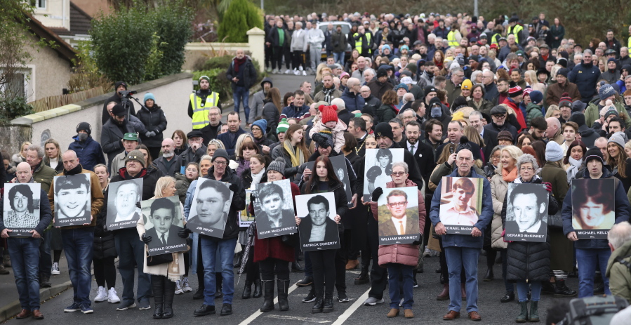 People take part in a march to commemorate the 50th anniversary of the 'Bloody Sunday' shootings with the photographs of some of the victims in Londonderry, Sunday, Jan. 30, 2022. In 1972 British soldiers shot 28 unarmed civilians at a civil rights march, killing 13 on what is known as Bloody Sunday or the Bogside Massacre.