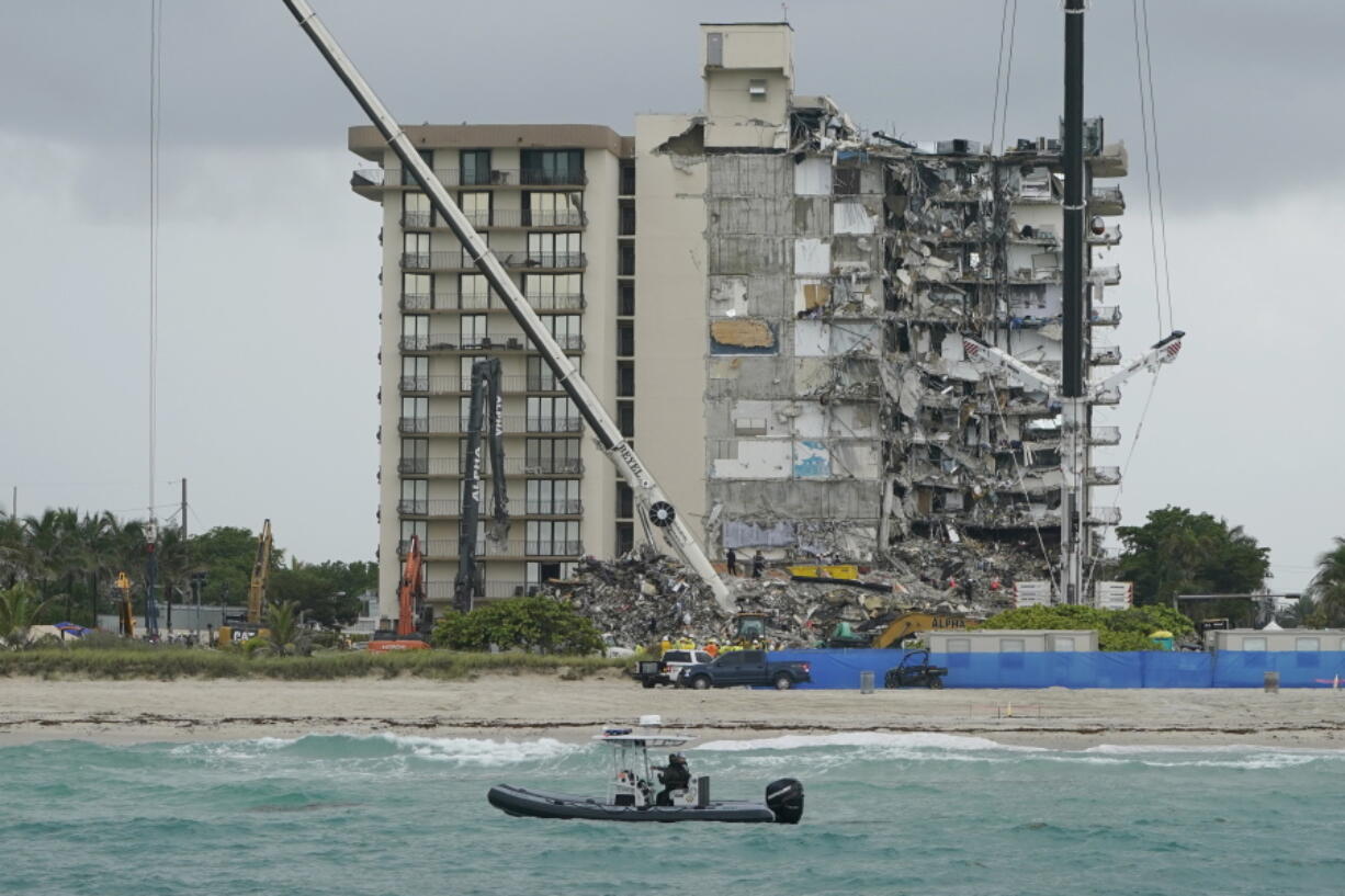 FILE - A Florida Fish and Wildlife Conservation law enforcement boat patrols in the ocean in front of search and rescue efforts at the Champlain Towers South condo building, where scores of people remain missing almost a week after it partially collapsed, Wednesday, June 30, 2021, in Surfside, Fla. A Florida grand jury issued a lengthy list of recommendations Wednesday, Dec. 15, aimed at preventing another condominium collapse like the one that killed 98 people in June, including earlier and more frequent inspections and better waterproofing.