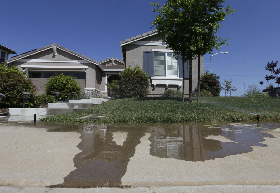 FILE -- Water flows down a sidewalk from water sprinklers running at a home Thursday, April 2, 2015, in Rancho Cordova, Calif. The State Water Resources Control Board voted Tuesday, Jan. 4, 2022 to adopt mandatory water use restrictions that prohibit excessive runoff from sprinklers.
