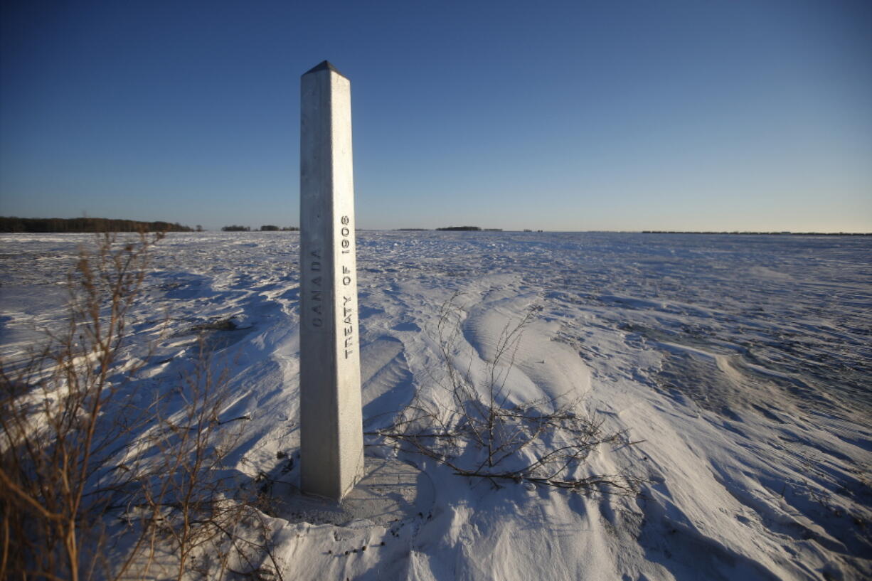 A border marker, between the United States and Canada is shown just outside of Emerson, Manitoba, on Thursday, Jan. 20, 2022.  A Florida man was charged Thursday with human smuggling after the bodies of four people, including a baby and a teen, were found in Canada near the U.S. border, in what authorities believe was a failed crossing attempt during a freezing blizzard. The bodies were found Wednesday in the province of Manitoba just meters (yards) from the U.S. border near the community of Emerson.