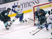 Vancouver Canucks left wing Nils Hoglander (21) passes the puck to center Bo Horvat (53) as Seattle Kraken center Colin Blackwell (43) defends in front of goaltender Philipp Grubauer during the first period of an NHL hockey game, Saturday, Jan. 1, 2022, in Seattle. (AP Photo/Ted S.