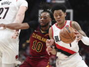 Cleveland Cavaliers guard Darius Garland defends against Portland Trail Blazers guard Anfernee Simons, right, during the first half of an NBA basketball game in Portland, Ore., Friday, Jan. 7, 2022.