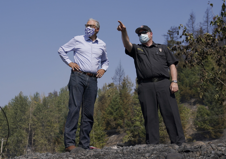 Washington Gov. Jay Inslee, left, talks with East Pierce Fire and Rescue Chief Bud Backer, right, Sept. 9, 2020, during a tour to survey wildfire damage in Bonney Lake, Wash., south of Seattle. Democratic governors such as California's Gavin Newsom and Washington's Inslee have been clear about their plans to boost spending on climate-related projects, including expanding access to electric vehicles and creating more storage for clean energies such as solar. (AP Photo/Ted S.