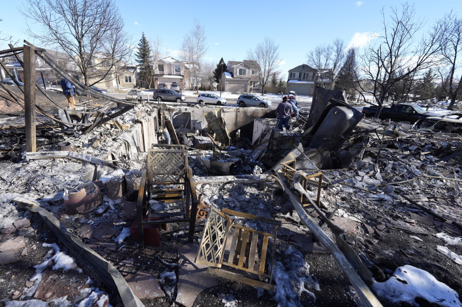 Members of the Stephens family sift through the remains of their home destroyed by wildfires Tuesday, Jan. 4, 2022, in Superior, Colo.