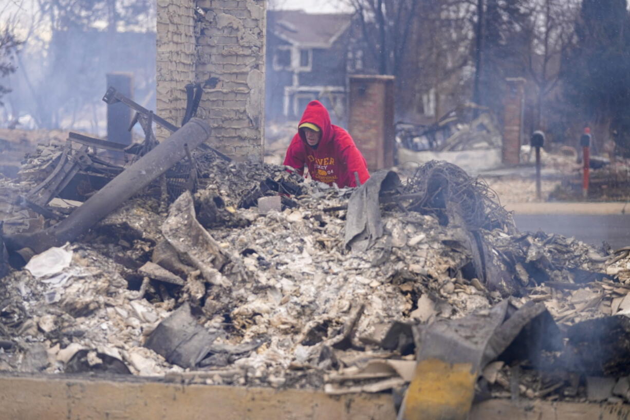 Todd Lovrien looks over the fire damage from the Marshall Wildfire at his sisters home in Louisville, Colo., Friday, Dec. 31, 2021. Tens of thousands of Coloradans driven from their neighborhoods by a wind-whipped wildfire anxiously waited to learn what was left standing of their lives Friday as authorities reported more than 500 homes were feared destroyed.