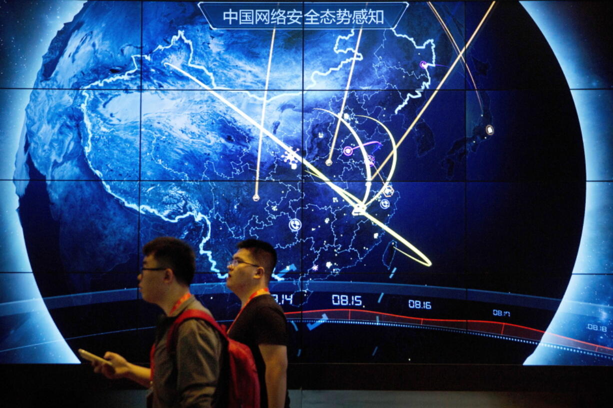 FILE - In this Sept. 12, 2017, file photo, attendees walk past an electronic display showing recent cyberattacks in China at the China Internet Security Conference in Beijing. Cybersecurity and space are emerging risks to the global economy, adding to existing challenges posed by climate change and the coronavirus pandemic, the World Economic Forum said in a report Tuesday, Jan. 11, 2022.