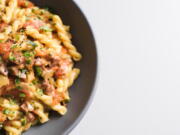 This image released by Milk Street shows a recipe for Gemelli w/Tomatoes, Salami and Fontina.