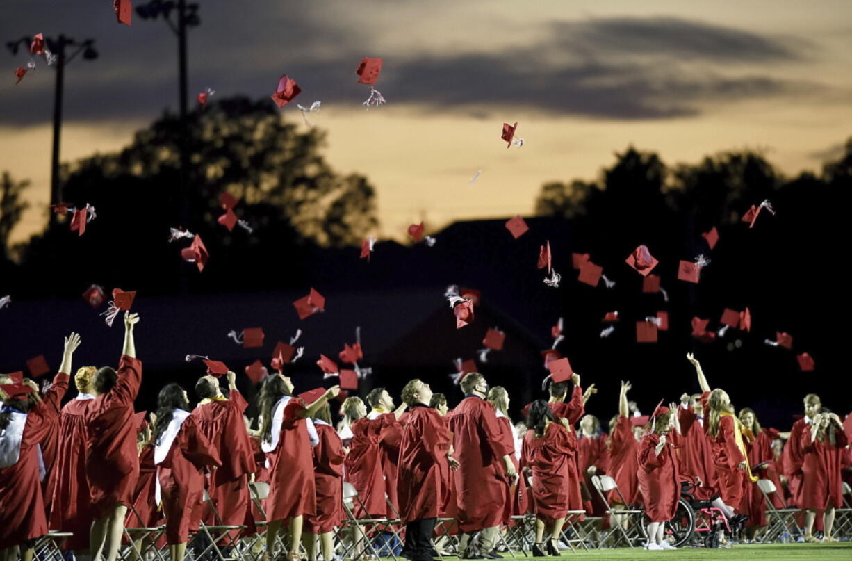 FILE - Red mortarboards fly into the evening sky at Heritage High School's commencement ceremony Friday, July 24, 2020, in Maryville Tenn.  High school graduation rates dipped in at least 20 states after the first full school year disrupted by the pandemic, according to a new analysis by Chalkbeat.