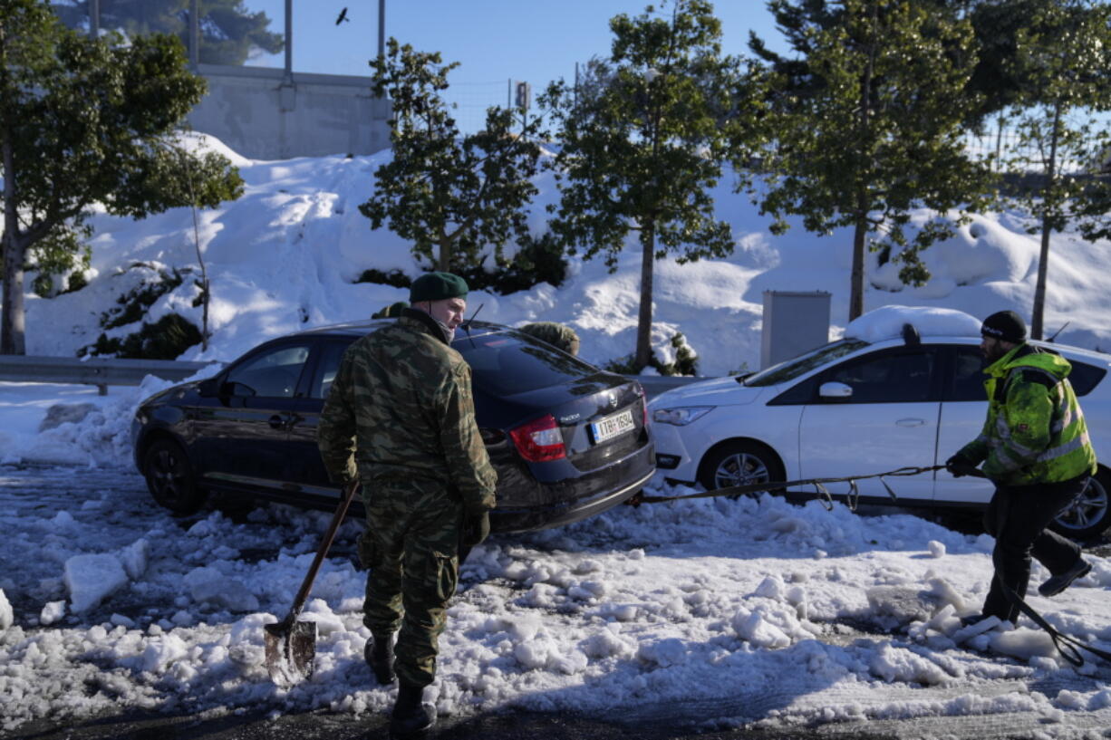 Greek soldiers try to free a vehicle stuck in snow on the Attiki Odos motorway, following Tuesday's heavy snowfall, in Athens, on Wednesday, Jan. 26, 2022.