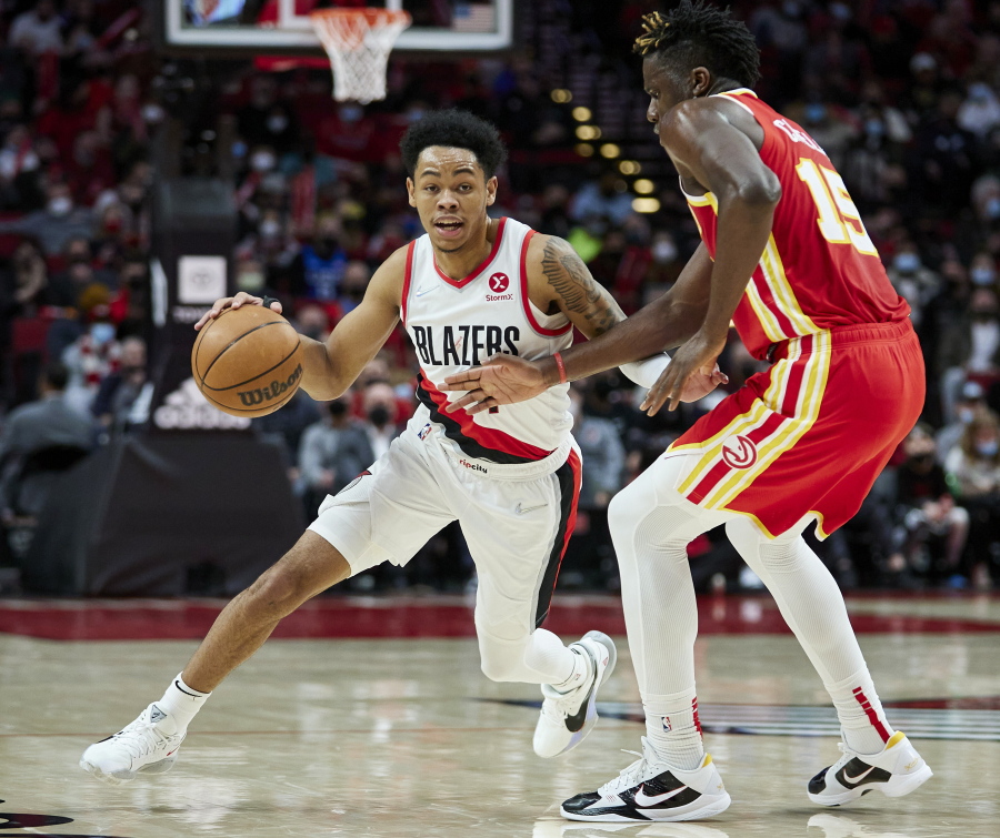 Portland Trail Blazers guard Anfernee Simons, left, dribbles around Atlanta Hawks center Clint Capela during the second half of an NBA basketball game in Portland, Ore., Monday, Jan. 3, 2022.