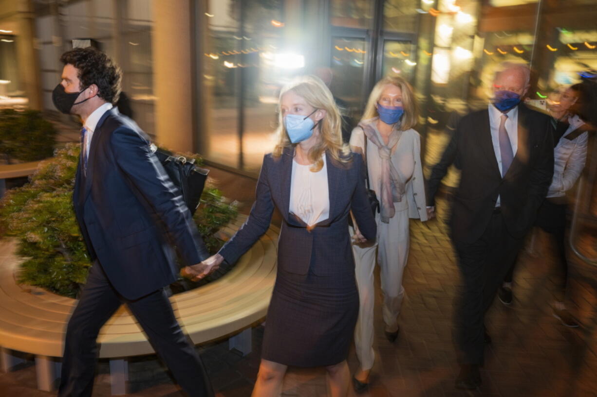 Elizabeth Holmes, second from left, walks out of federal court in San Jose, Calif., Friday, Dec. 17, 2021.